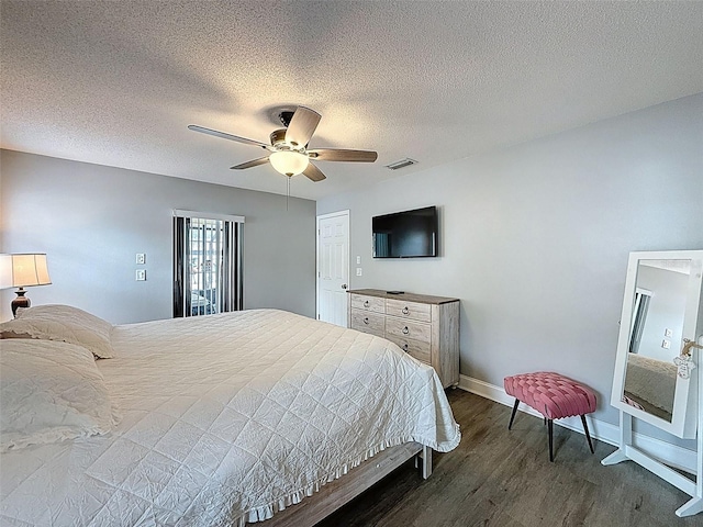 bedroom with visible vents, baseboards, dark wood-style floors, a textured ceiling, and a ceiling fan