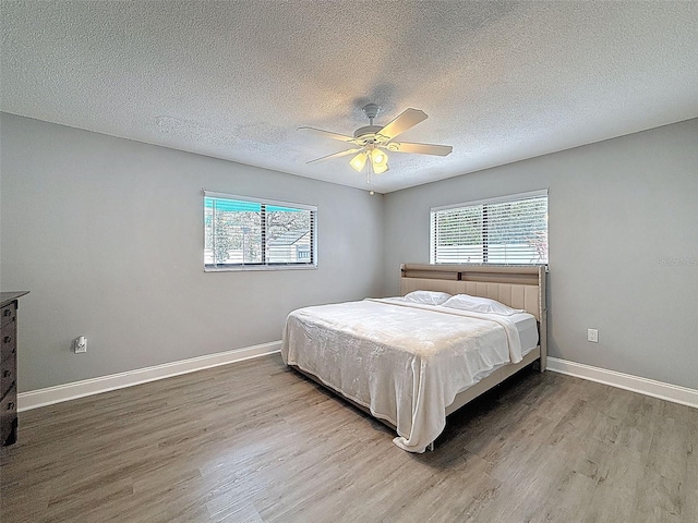 bedroom featuring a textured ceiling, a ceiling fan, baseboards, and wood finished floors