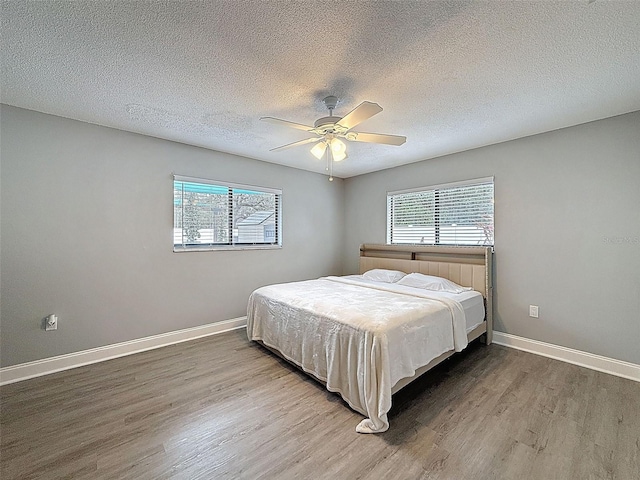 bedroom with multiple windows, wood finished floors, and baseboards