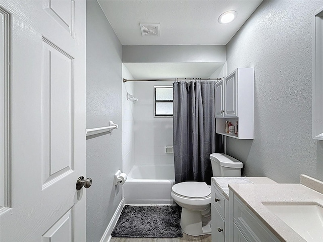 bathroom featuring visible vents, toilet, vanity, and a textured wall