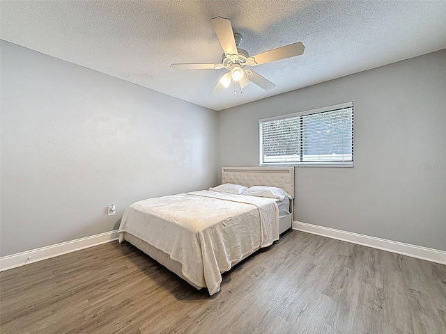 bedroom featuring wood finished floors, baseboards, and a textured ceiling