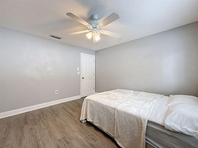 bedroom with visible vents, ceiling fan, baseboards, dark wood finished floors, and a textured ceiling