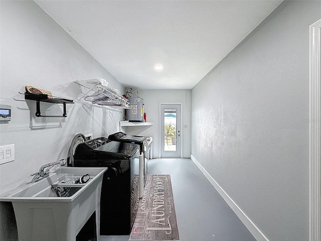 laundry area featuring washing machine and clothes dryer, baseboards, laundry area, a textured wall, and a sink