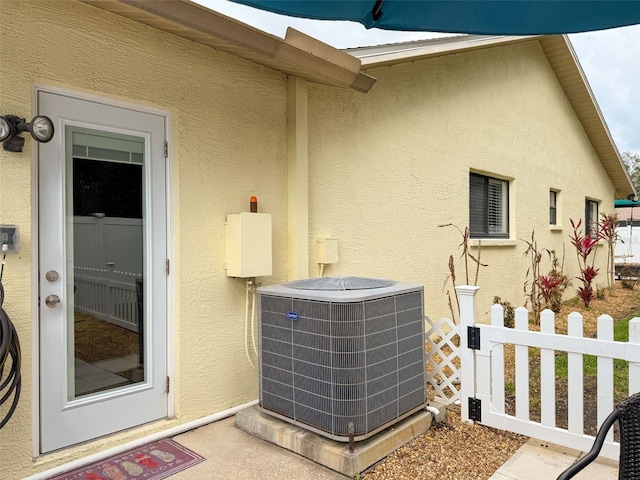 exterior space featuring stucco siding, central AC, and fence