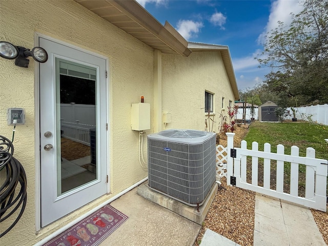 exterior space with central AC unit, fence, and stucco siding