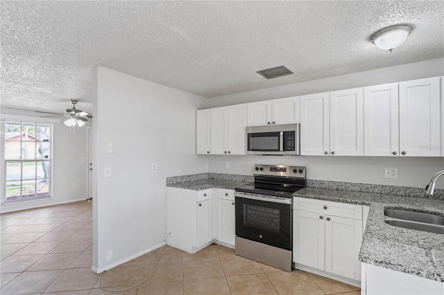 kitchen featuring visible vents, appliances with stainless steel finishes, light tile patterned flooring, white cabinets, and a sink