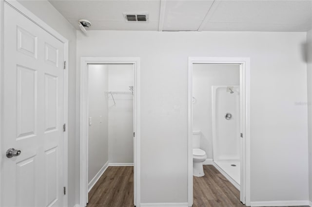 bathroom with visible vents, a shower stall, baseboards, toilet, and wood finished floors