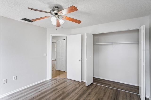 unfurnished bedroom featuring a ceiling fan, visible vents, wood finished floors, a closet, and a textured ceiling