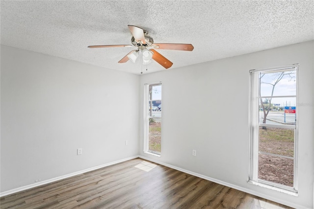 unfurnished room with baseboards, plenty of natural light, a textured ceiling, and wood finished floors