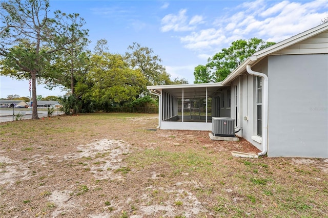 view of yard with central AC, fence, and a sunroom