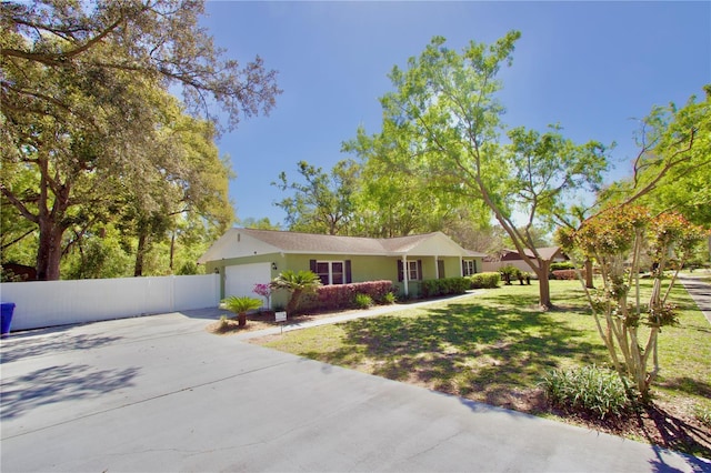 ranch-style house with a front yard, concrete driveway, an attached garage, and fence