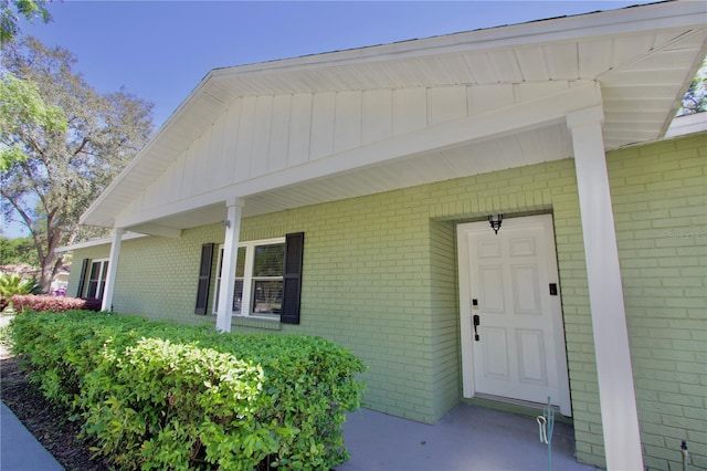 entrance to property featuring brick siding and covered porch