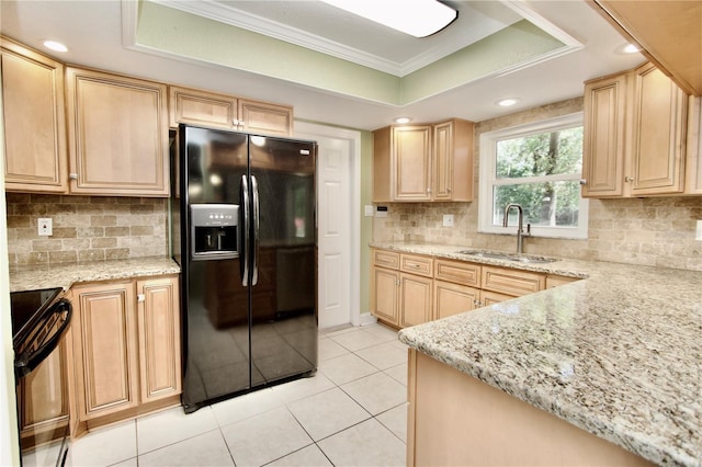 kitchen with light brown cabinets, a tray ceiling, stove, black fridge with ice dispenser, and a sink