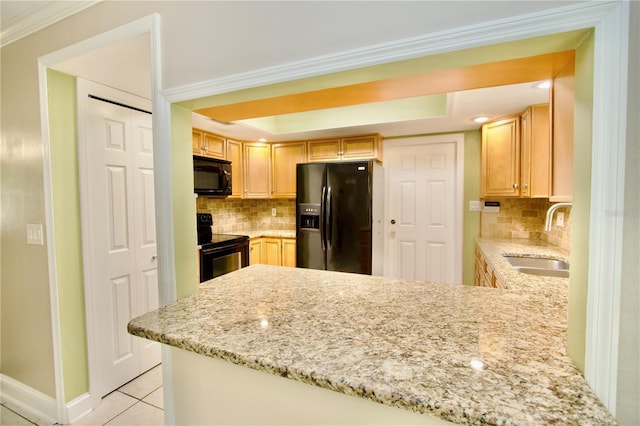 kitchen with light tile patterned floors, a peninsula, a sink, black appliances, and a raised ceiling