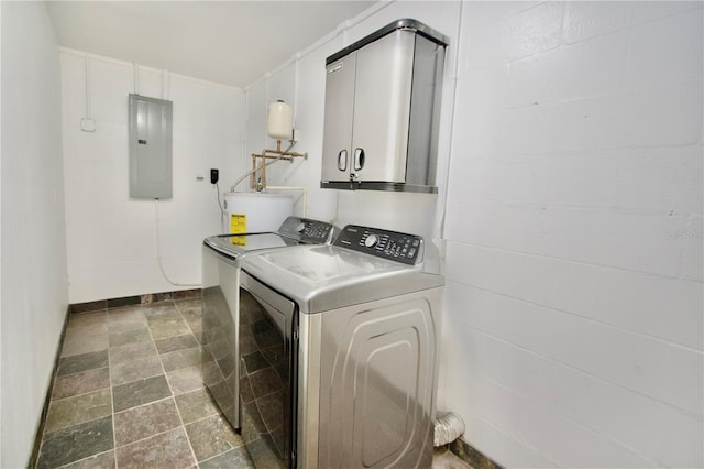 laundry room with stone finish floor, electric panel, washing machine and dryer, water heater, and cabinet space