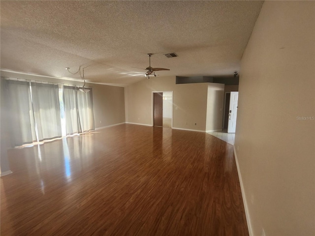 empty room featuring visible vents, a ceiling fan, a textured ceiling, wood finished floors, and baseboards