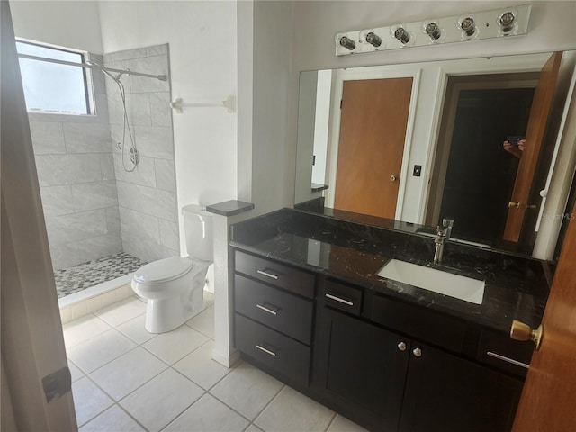 bathroom with vanity, tile patterned floors, toilet, and tiled shower
