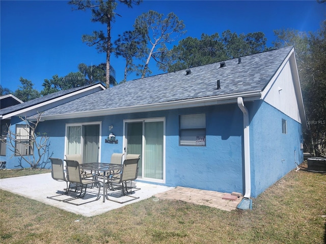rear view of house featuring a yard, central air condition unit, a patio area, and roof with shingles
