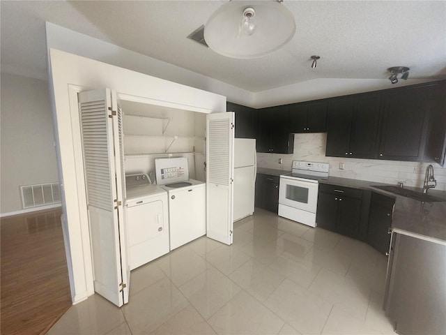 kitchen with visible vents, a sink, white appliances, separate washer and dryer, and vaulted ceiling