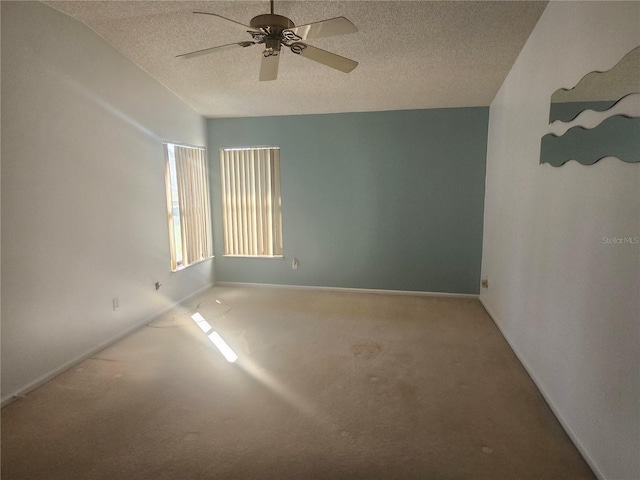 carpeted spare room with baseboards, a textured ceiling, and a ceiling fan