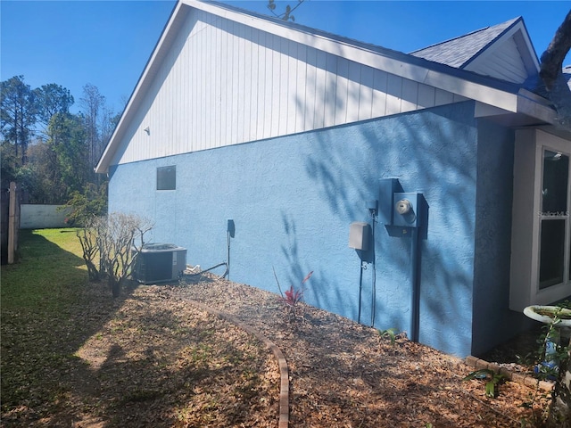 view of side of property with cooling unit, a yard, and fence