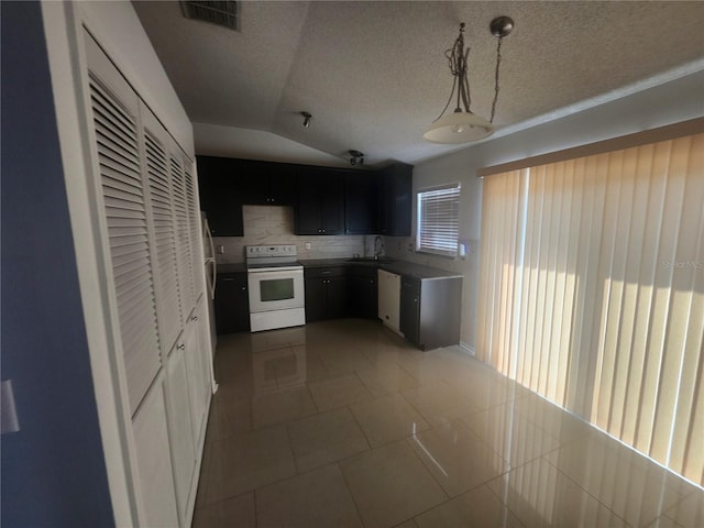 kitchen featuring tile patterned flooring, visible vents, decorative backsplash, white appliances, and a textured ceiling