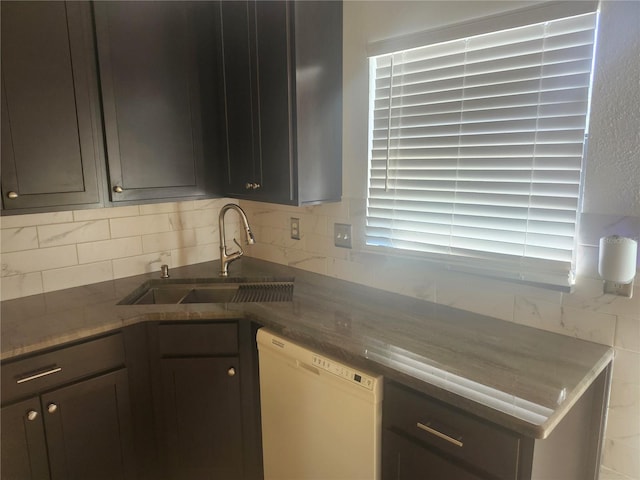 kitchen with a sink, backsplash, and white dishwasher