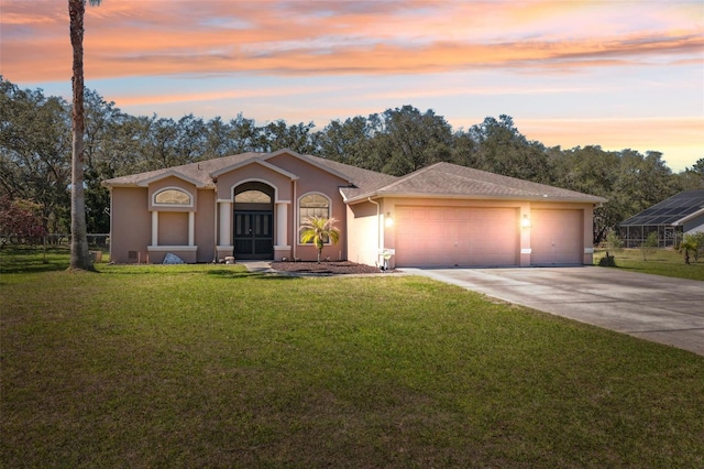 view of front of home with stucco siding, a lawn, driveway, fence, and an attached garage