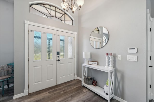 foyer entrance with dark wood finished floors, an inviting chandelier, and baseboards