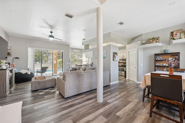 living area with a ceiling fan, wood finished floors, visible vents, and a textured ceiling