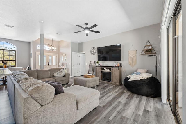 living room with lofted ceiling, wood finished floors, and ceiling fan with notable chandelier