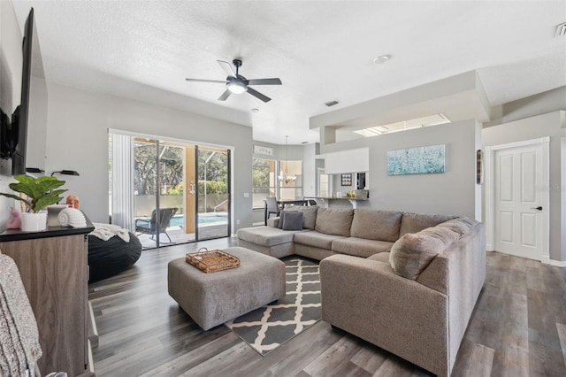 living room with visible vents, wood finished floors, and ceiling fan with notable chandelier