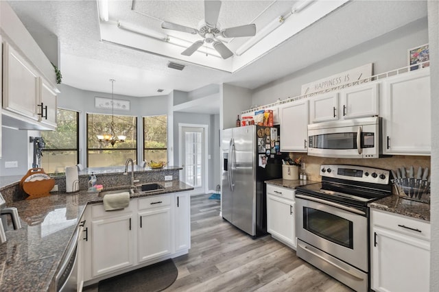 kitchen featuring a tray ceiling, stainless steel appliances, visible vents, and white cabinets