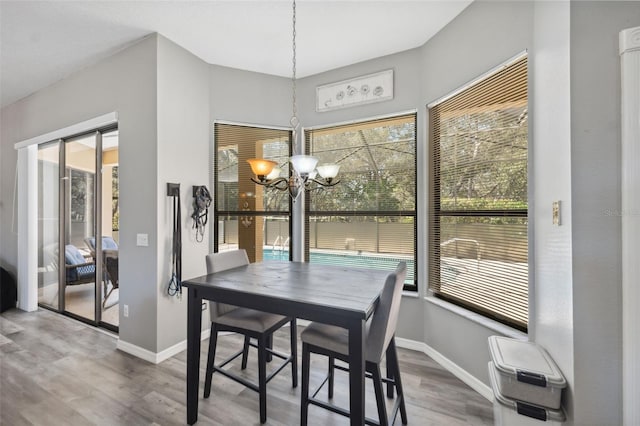 dining space featuring a wealth of natural light, a notable chandelier, baseboards, and wood finished floors