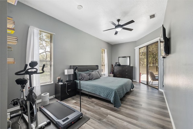 bedroom with baseboards, wood finished floors, a textured ceiling, and access to exterior