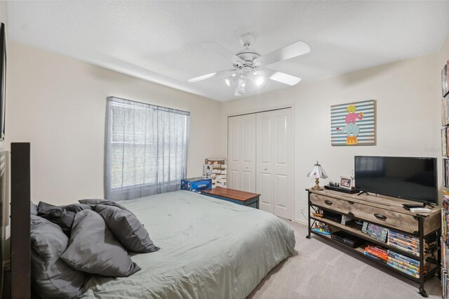 bedroom featuring light carpet, a ceiling fan, and a closet