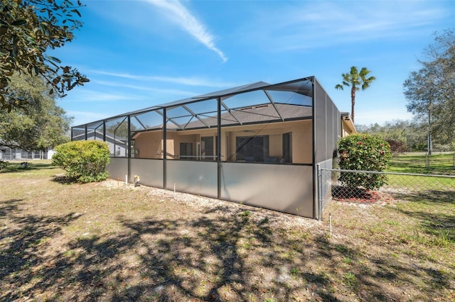 back of house with a lanai, stucco siding, a yard, and fence