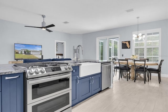 kitchen with a sink, blue cabinetry, plenty of natural light, and stainless steel appliances