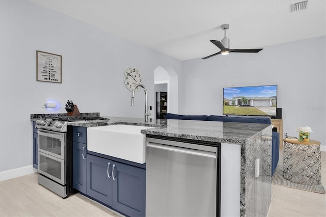 kitchen featuring visible vents, ceiling fan, stone countertops, stainless steel appliances, and a sink