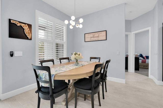 dining area featuring baseboards, light wood-style floors, and a chandelier