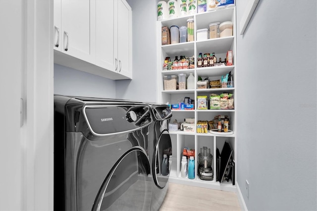 laundry area featuring cabinet space, wood finished floors, and washer and clothes dryer