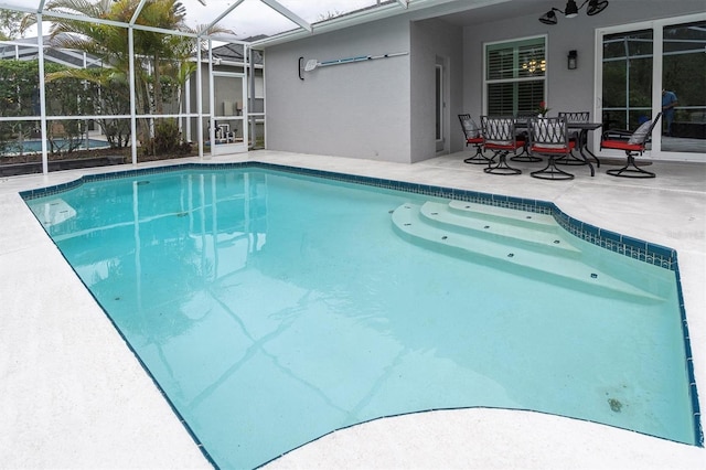 outdoor pool with glass enclosure and a patio area