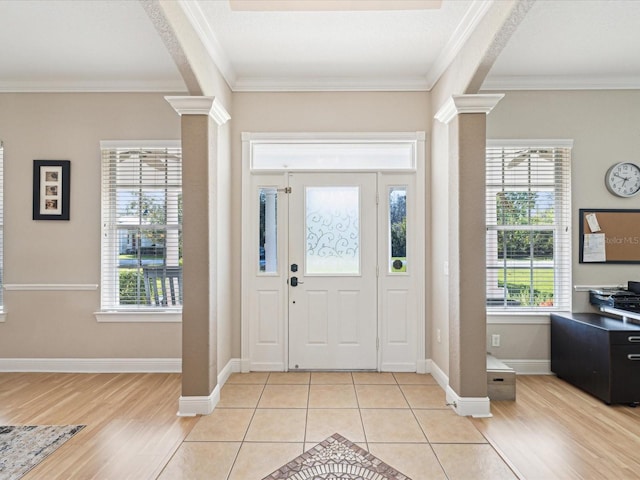 foyer entrance featuring a healthy amount of sunlight, crown molding, and ornate columns