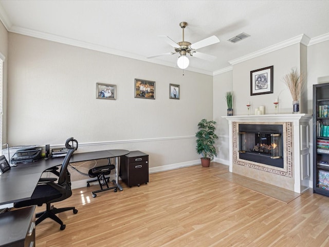 home office with wood finished floors, crown molding, a fireplace, and visible vents