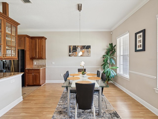 dining room with light wood-style flooring, baseboards, and ornamental molding