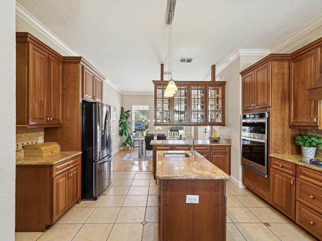 kitchen with visible vents, an island with sink, a sink, appliances with stainless steel finishes, and light tile patterned floors