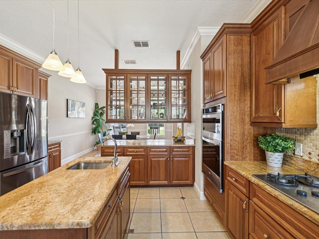 kitchen featuring tasteful backsplash, brown cabinets, appliances with stainless steel finishes, custom exhaust hood, and a sink