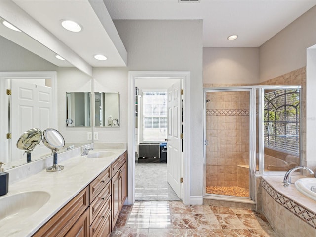 bathroom featuring double vanity, a stall shower, a garden tub, and a sink