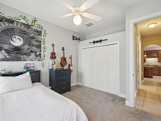 bedroom featuring visible vents, arched walkways, a closet, and light carpet