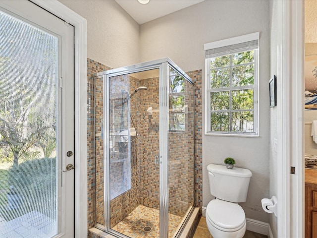 bathroom with a shower stall, toilet, and baseboards